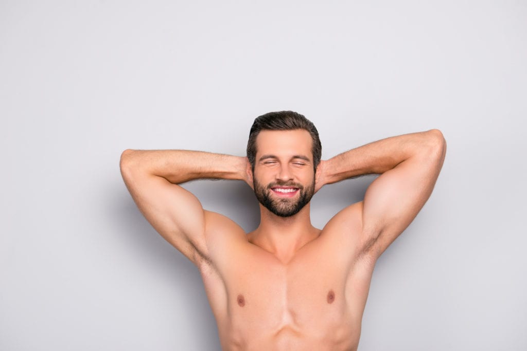image of a shirtless man with his arms crossed behind his head after laser hair removal