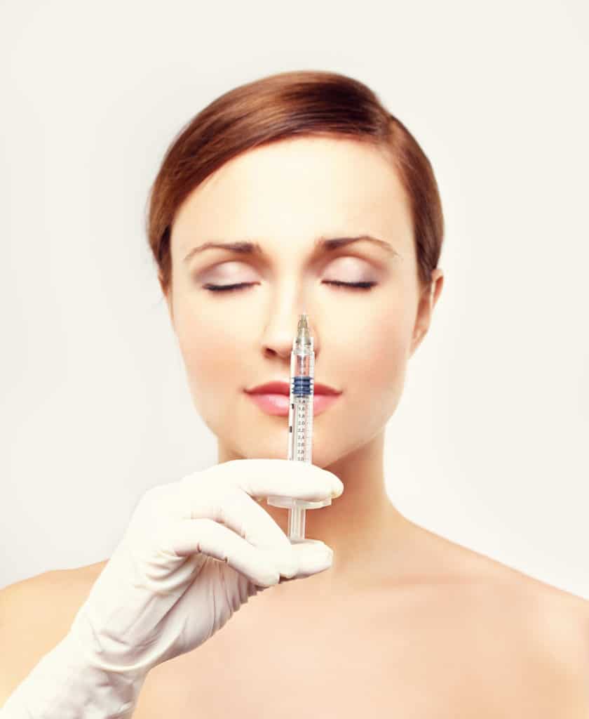 A woman holding a syringe preparing to recieve dermal filler Injection of beauty products.