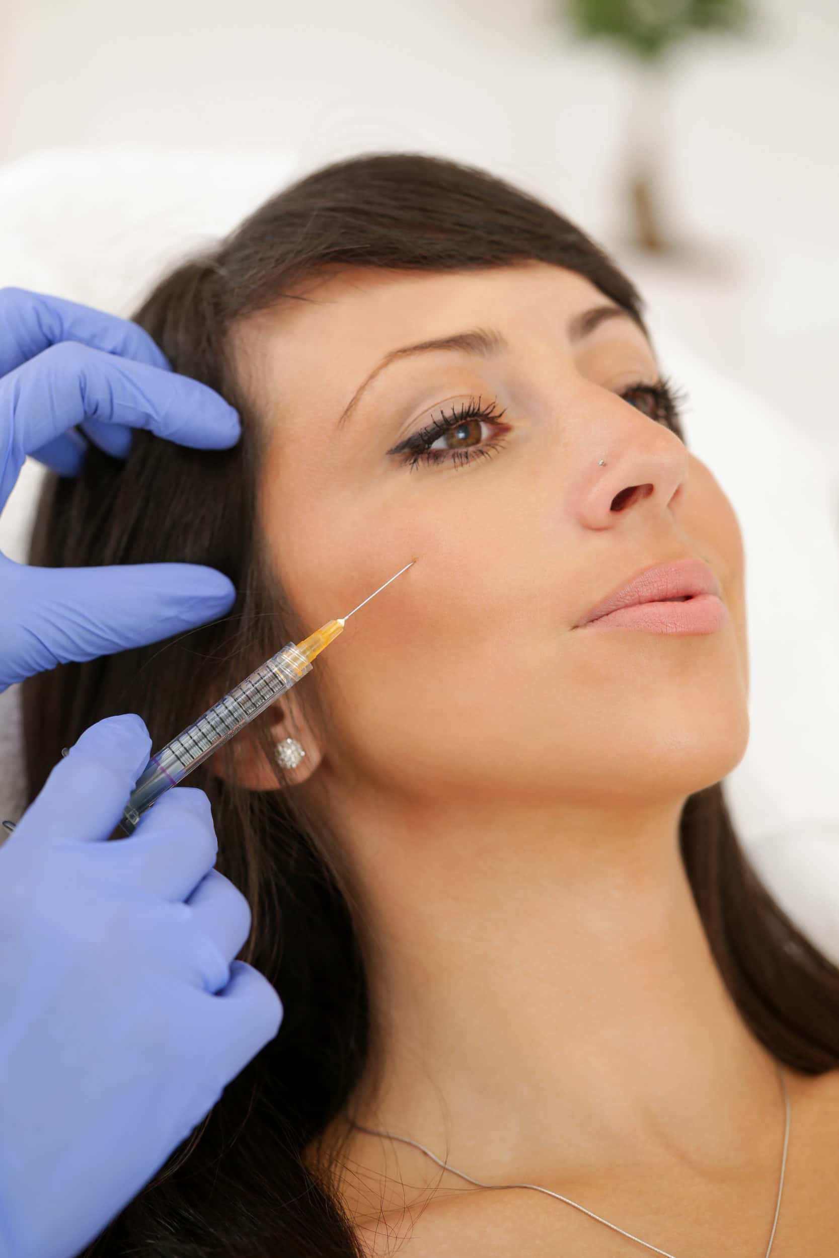 Female doctor injecting hyaloronan fillers into woman's cheek