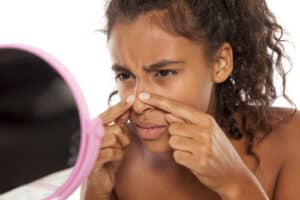 young beautiful black woman squeezing pimples on her nose